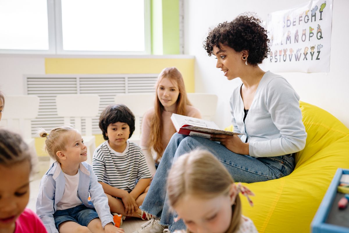 A woman reading a book to a group of children